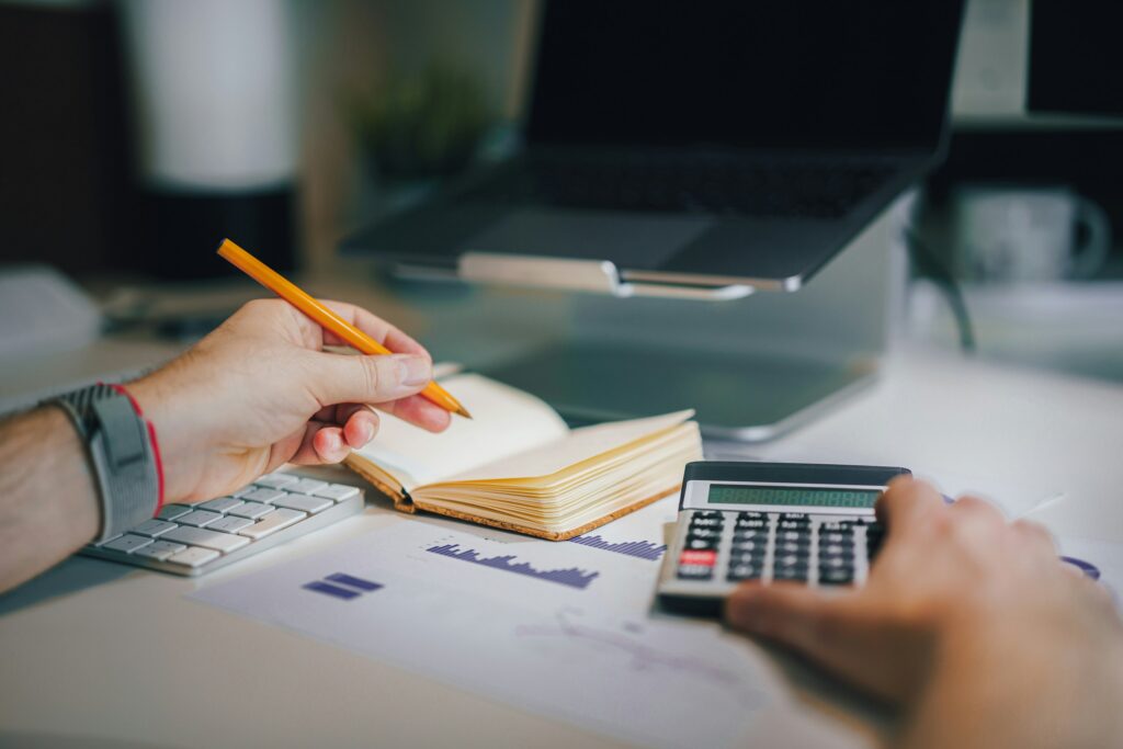 a person sitting at a desk with a calculator and a notebook a person sitting at a desk with a calculator and a notebook